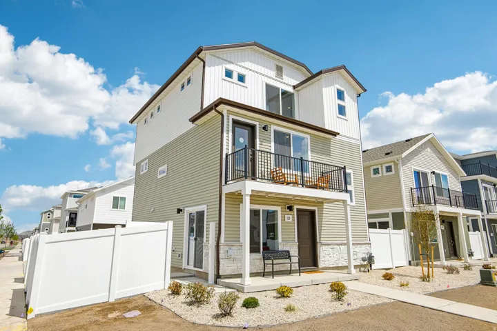 Contemporary multi-story exterior with horizontal siding, stone veneer accents, and multiple balconies with metal railings
