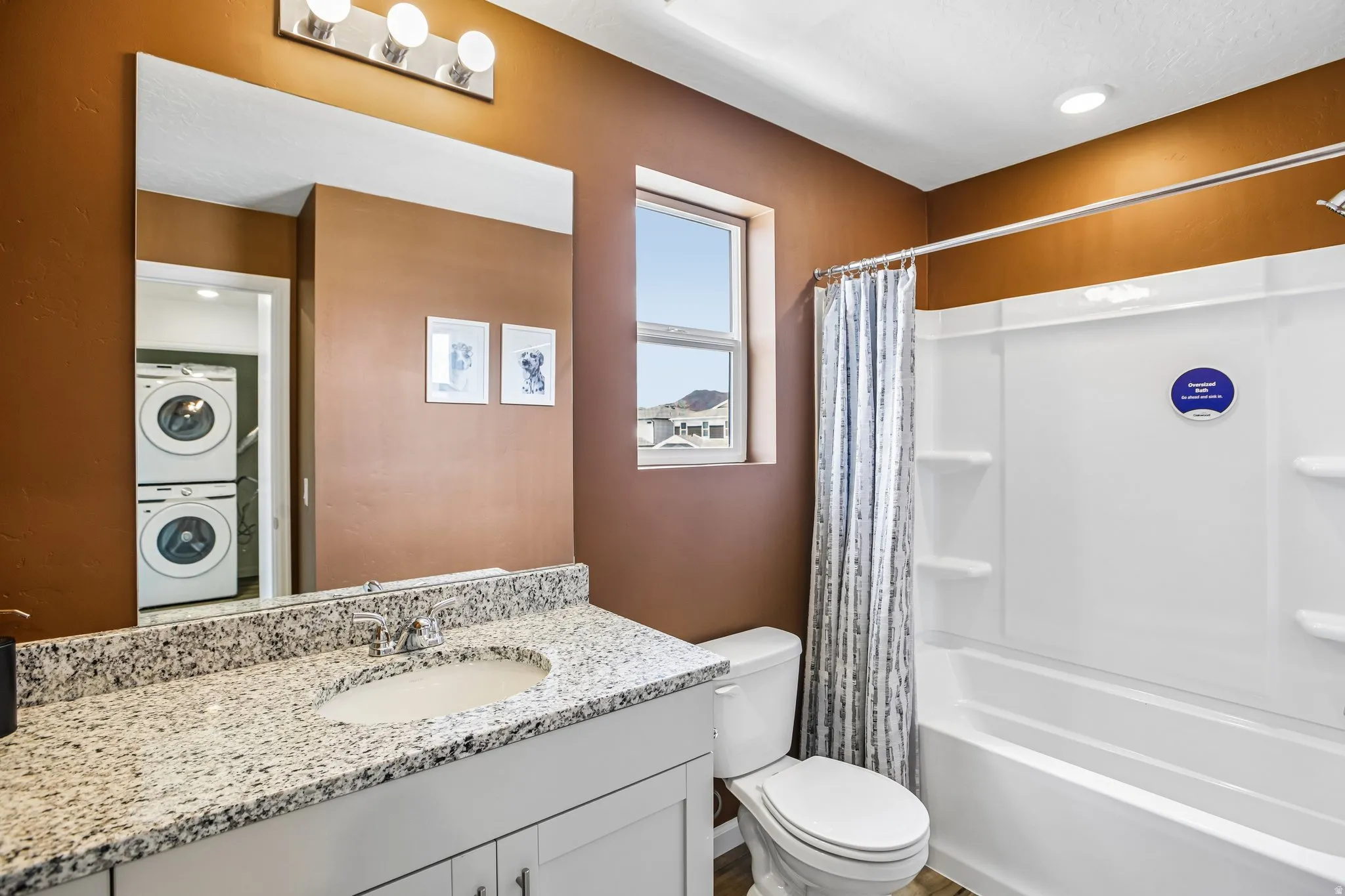 Bathroom featuring a single vanity with stone-finish countertop, under-mount sink, and chrome faucet