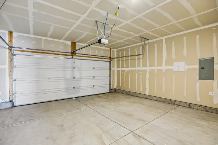 Spacious garage featuring a sectional overhead door, automatic opener, and concrete flooring