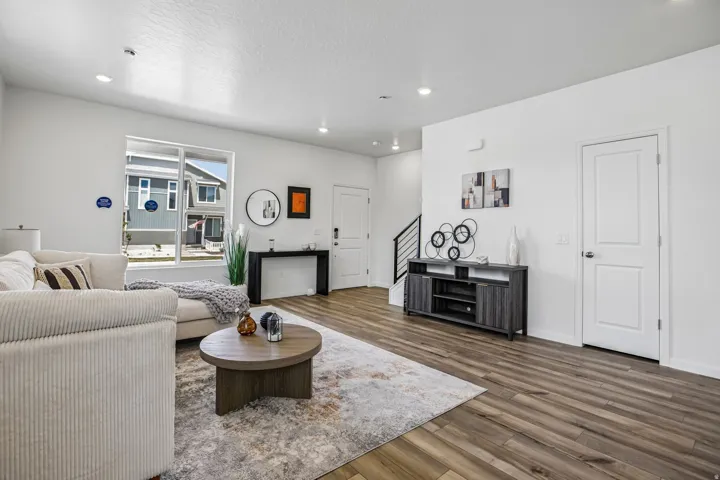 Open-concept living space with wood-finish flooring, recessed lighting, and large windows
