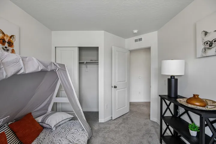 Neutral wall color with textured ceiling, soft gray carpeting, and a built-in closet with sliding doors
