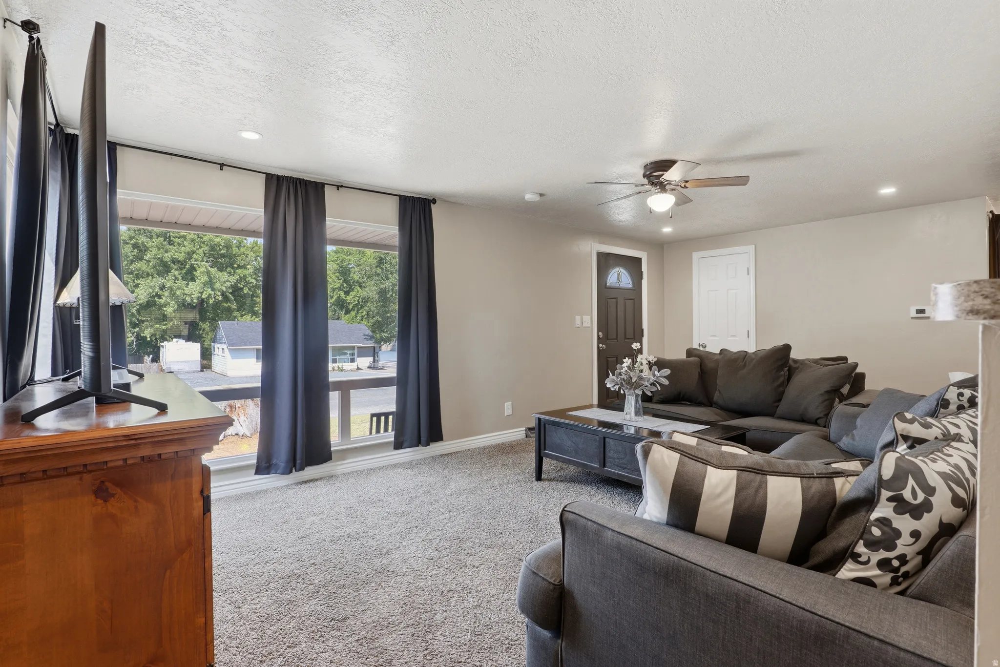 Recessed lighting, ceiling fan, carpet flooring, and a dark-paneled entry door