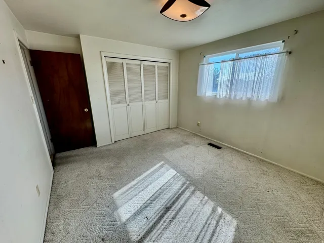 Wall-to-wall carpeting and a single pane window with sheers