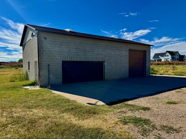Concrete block construction garage featuring two roll-up doors, a side entry door, and a shingle roof
