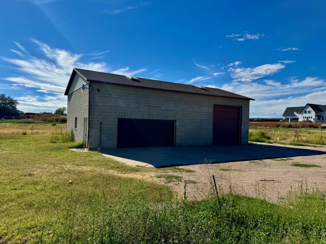 Block construction outbuilding with multiple garage doors and a paved approach