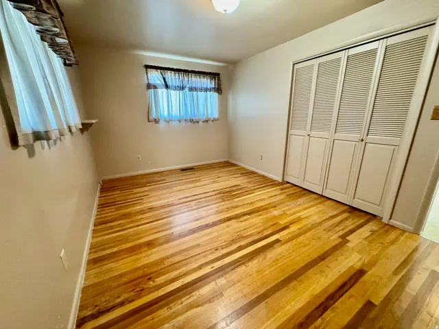 Hardwood flooring throughout, louvered bi-fold closet doors, and wall-mounted light fixture