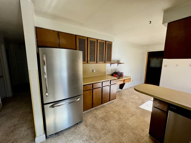 Kitchen with base and upper cabinetry, a built-in dishwasher, and an integrated counter seating area
