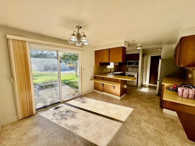 Eat-in kitchen featuring tile flooring, wood-finish cabinetry, and a sliding glass door leading to the backyard