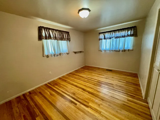 Wood-finish flooring with dual windows and a ceiling-mounted light fixture