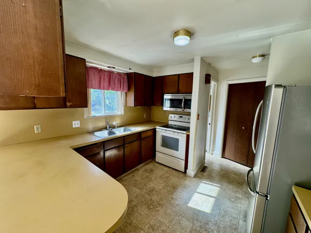 Kitchen featuring wood-finish cabinetry, a double basin stainless steel sink, tile flooring, and a built-in microwave