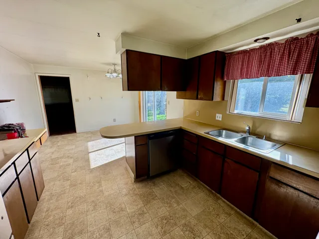 Kitchen featuring wood-finish cabinetry, a double basin stainless steel sink, and a built-in dishwasher