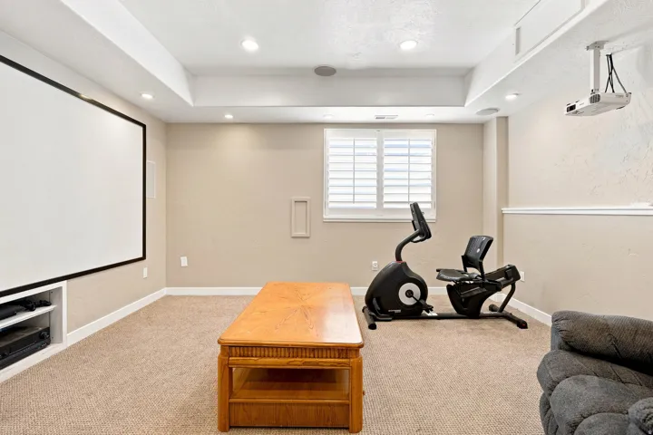 Recessed lighting, built-in display screen, ceiling-mounted projector, built-in media shelving, and window with plantation shutters