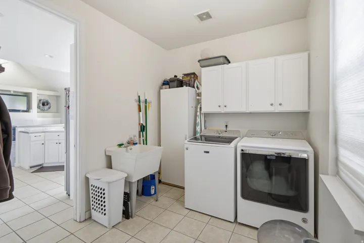 Laundry area featuring tile flooring, a utility sink, and white cabinetry