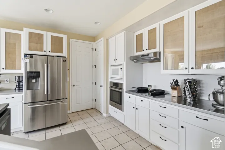 Kitchen featuring white cabinetry, stainless steel appliances, neutral tile flooring, and recessed lighting