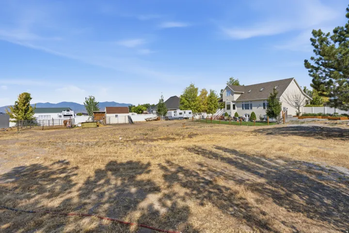 Spacious land parcel with open terrain, partially fenced perimeter, and distant mountain scenery