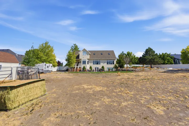 Spacious lot featuring a multi-story residence with a gabled roof, multiple windows, and a rear deck