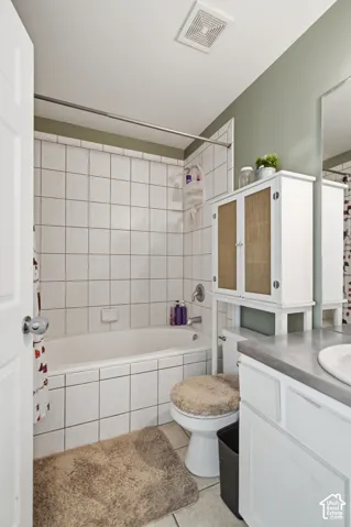 Bathtub with white tile surround, white vanity with integrated sink, and wall-mounted mirror