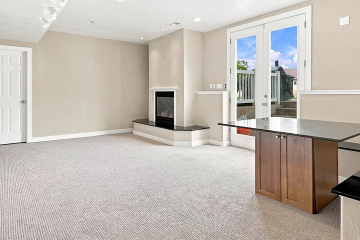 Recessed lighting, fireplace with a black stone hearth, carpeted flooring, French doors, and built-in cabinetry with a countertop