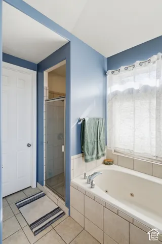 Tile flooring with a walk-in shower, built-in soaking tub, and tiled tub surround