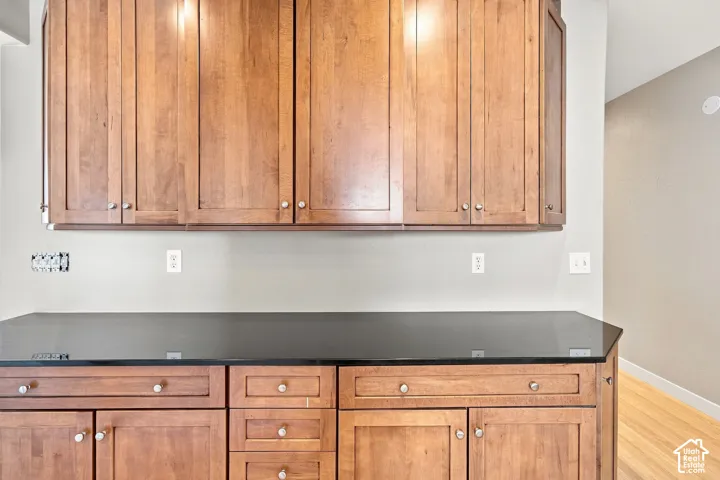 Wood-finish cabinetry with silver-tone hardware, dark countertop, and light wall paint