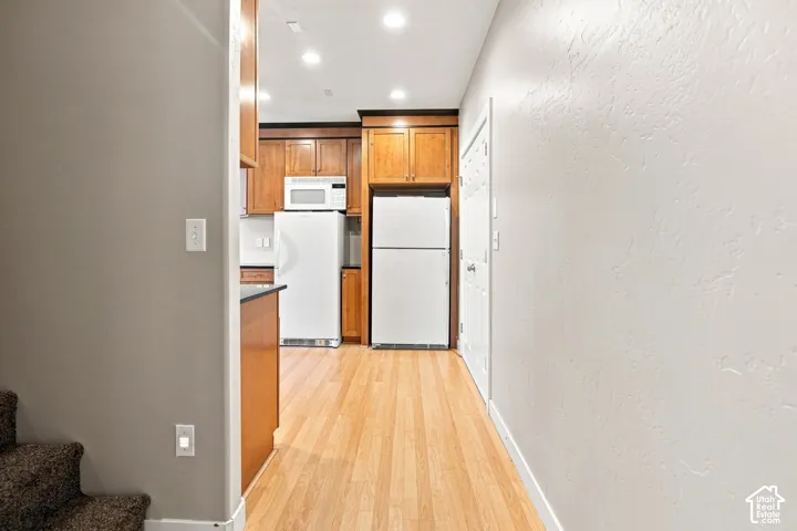 Kitchen featuring wood cabinetry, white appliances, and recessed lighting