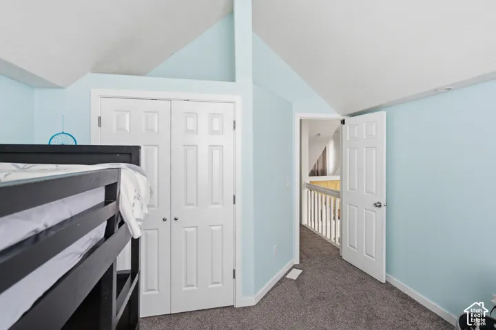 Vaulted ceiling, bi-fold closet doors, paneled interior door, carpeted flooring, interior railing