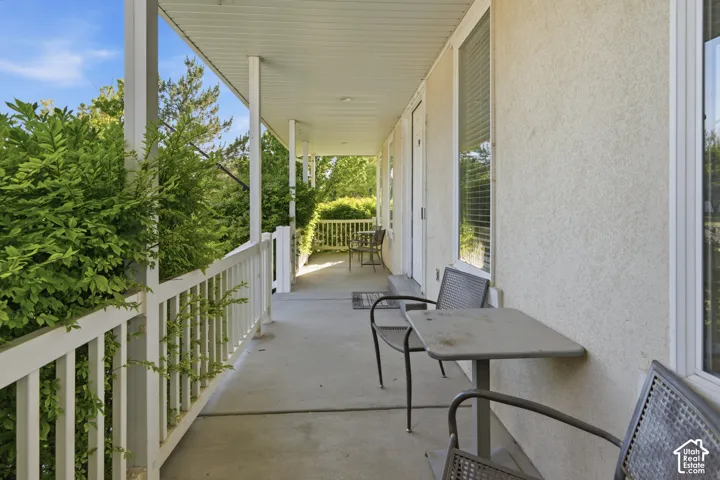 Covered porch with white railings and columns, featuring a textured stucco exterior and dual pane windows