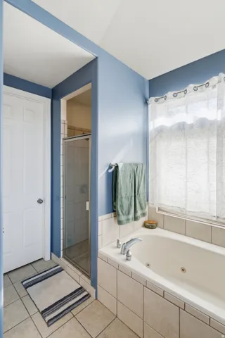 Tile flooring with a walk-in shower, built-in soaking tub, and tiled tub surround