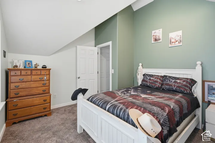 Vaulted ceiling with recessed lighting, two-panel interior doors, and carpet flooring