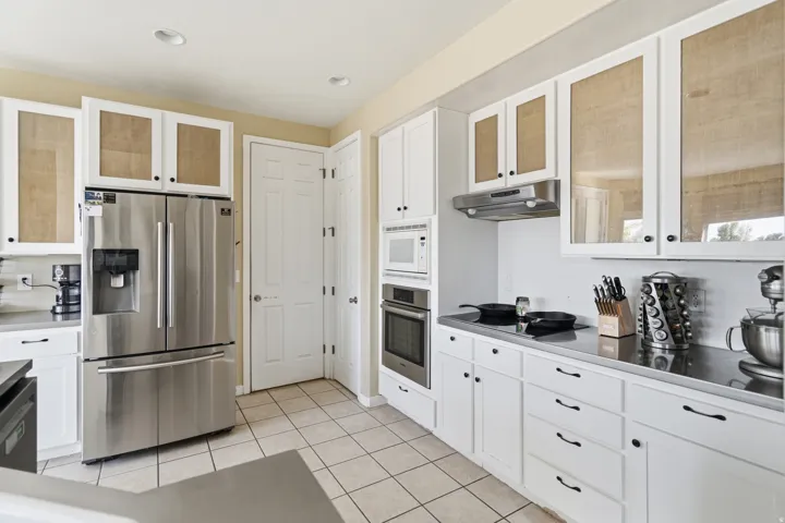 Kitchen featuring white cabinetry, stainless steel appliances, neutral tile flooring, and recessed lighting