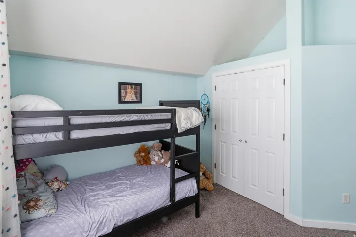 Light blue painted walls, vaulted ceiling, white paneled closet doors, and gray carpet flooring