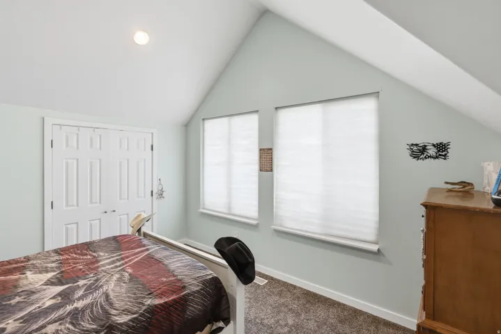 Vaulted ceiling, recessed lighting, double panel doors, two windows with blinds, and carpeted flooring