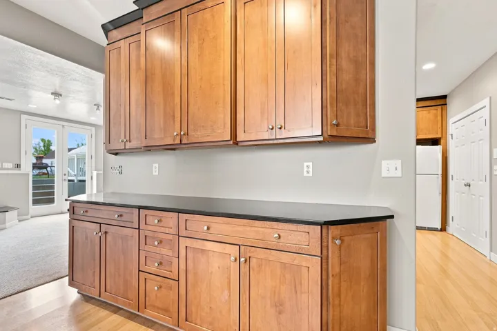 Extensive wood cabinetry with dark countertops, wood-finish flooring, and double French doors with transom windows