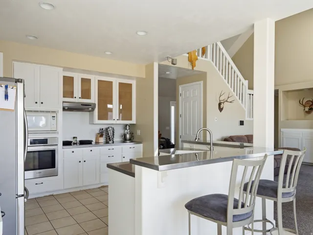 Open-concept kitchen with white cabinetry, stainless steel appliances, and tile flooring