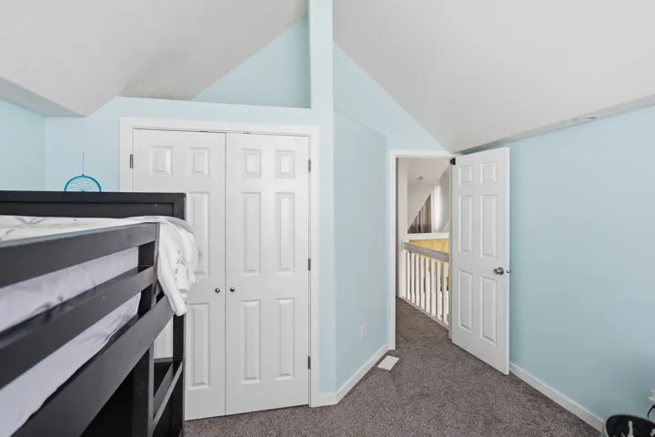 Vaulted ceiling, bi-fold closet doors, paneled interior door, carpeted flooring, interior railing