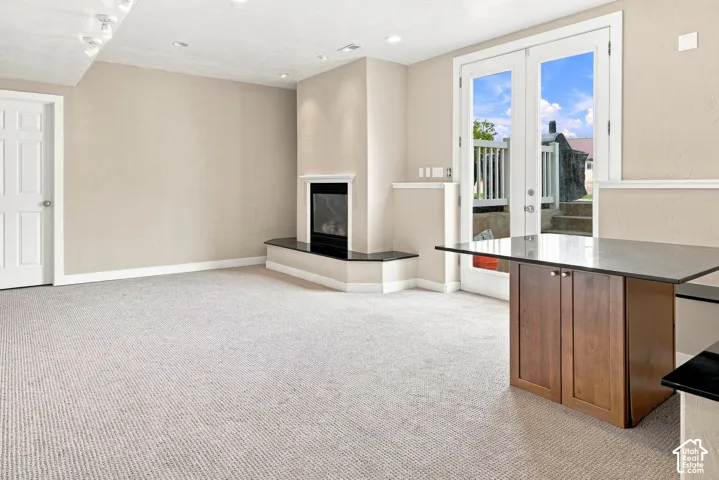 Recessed lighting, fireplace with a black stone hearth, carpeted flooring, French doors, and built-in cabinetry with a countertop