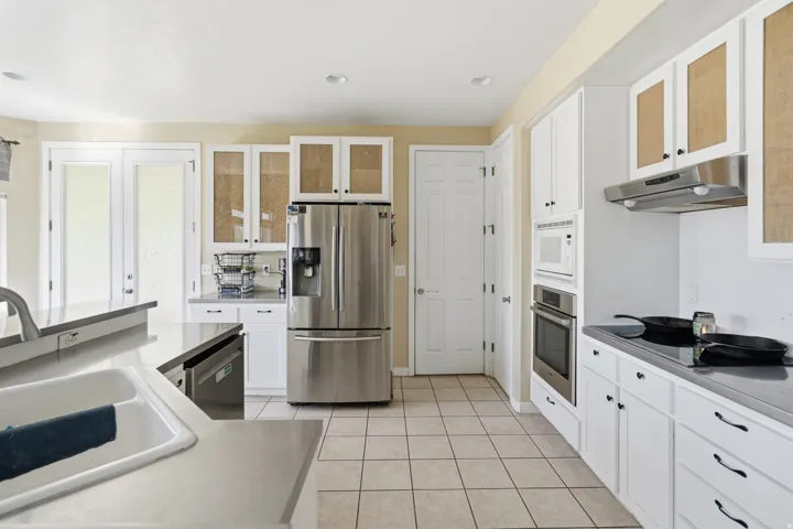 Kitchen featuring white cabinetry, stainless steel appliances, a built-in double oven, and tile flooring
