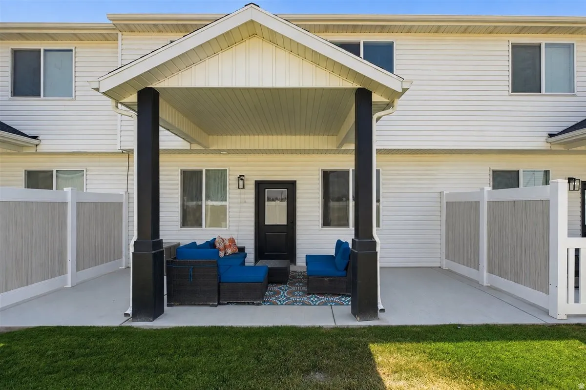 Covered patio with durable concrete flooring, black support columns, and white vinyl siding