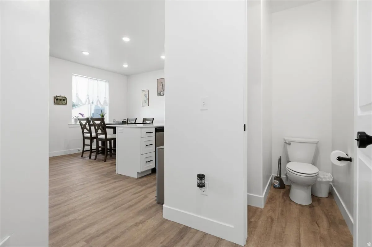 White walls, recessed lighting, and wood-finish flooring throughout