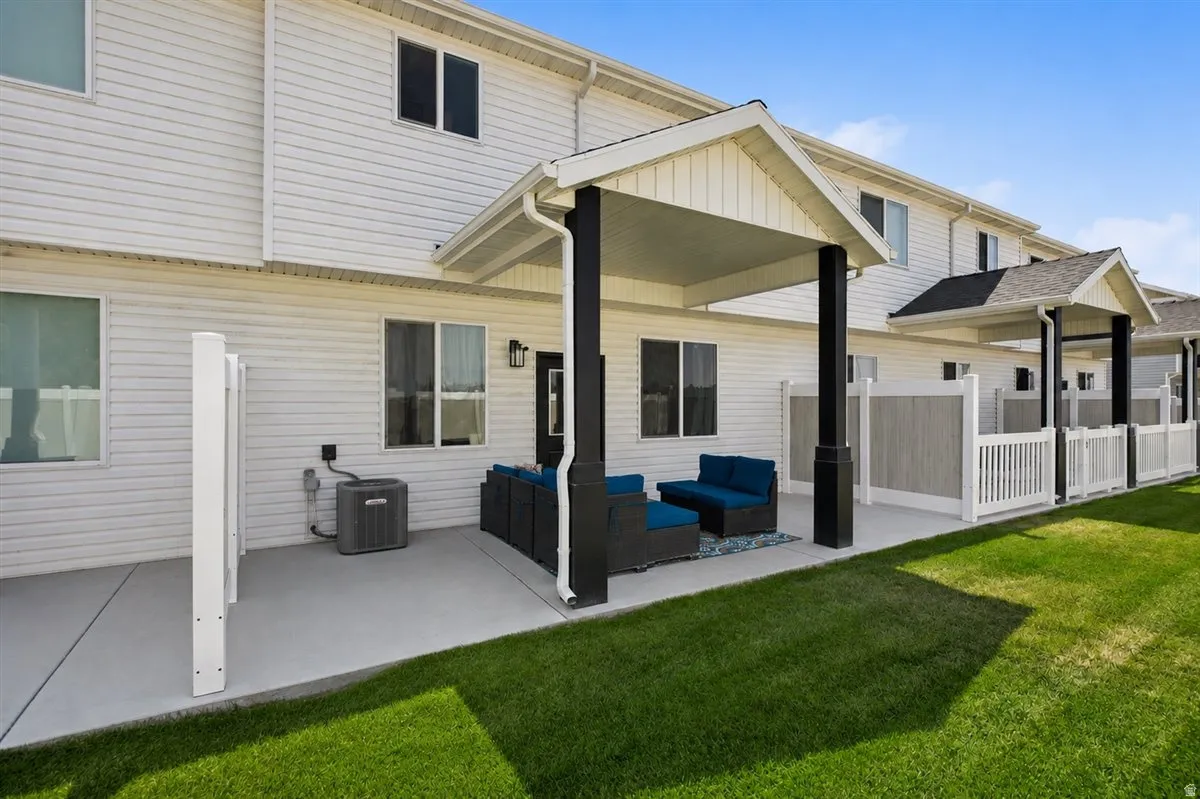 Covered patio with a concrete surface, white vinyl siding exterior, and a manicured lawn