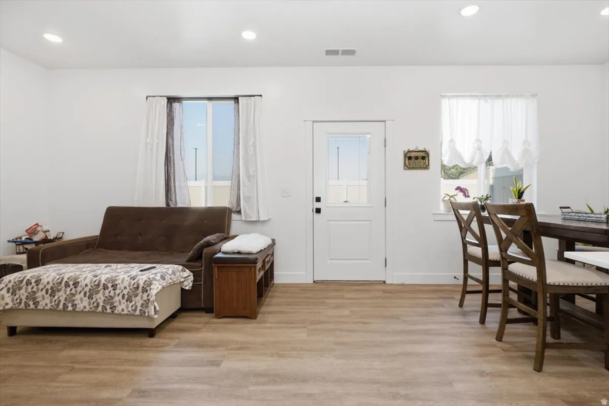 Recessed lighting, wood-finish flooring, white paneled door with glass insert, and white walls