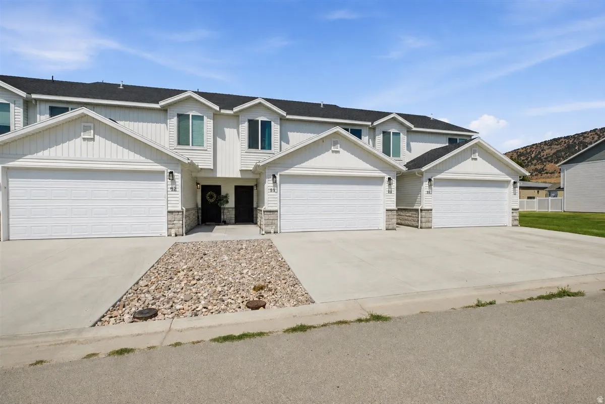 White siding exterior with multiple attached garages, bay windows, and prominent front entrances