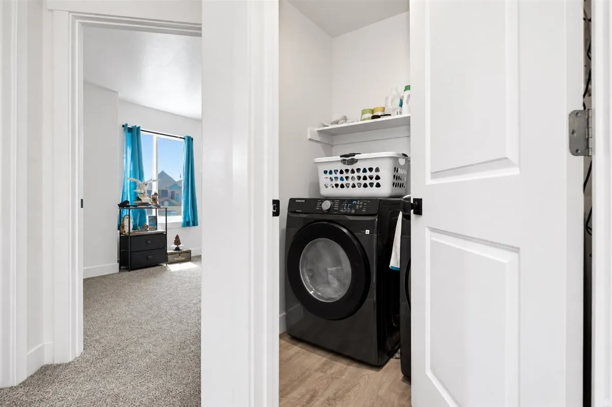 Dedicated laundry area with built-in shelving and wood-finish flooring
