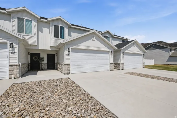 Multi-unit building featuring a stone and siding exterior, individual garages, and concrete driveways