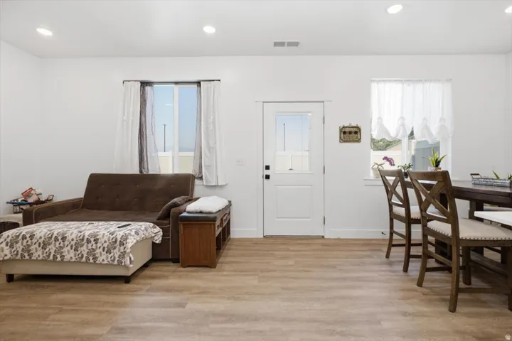 Recessed lighting, wood-finish flooring, white paneled door with glass insert, and white walls