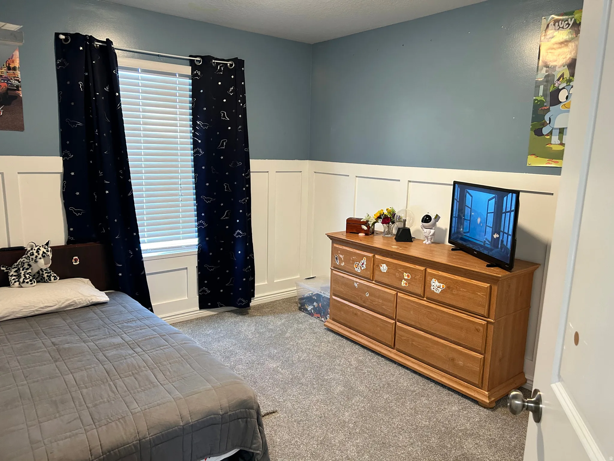 Board and batten wall detailing, window with horizontal blinds, light blue wall paint, gray carpet flooring, white interior door