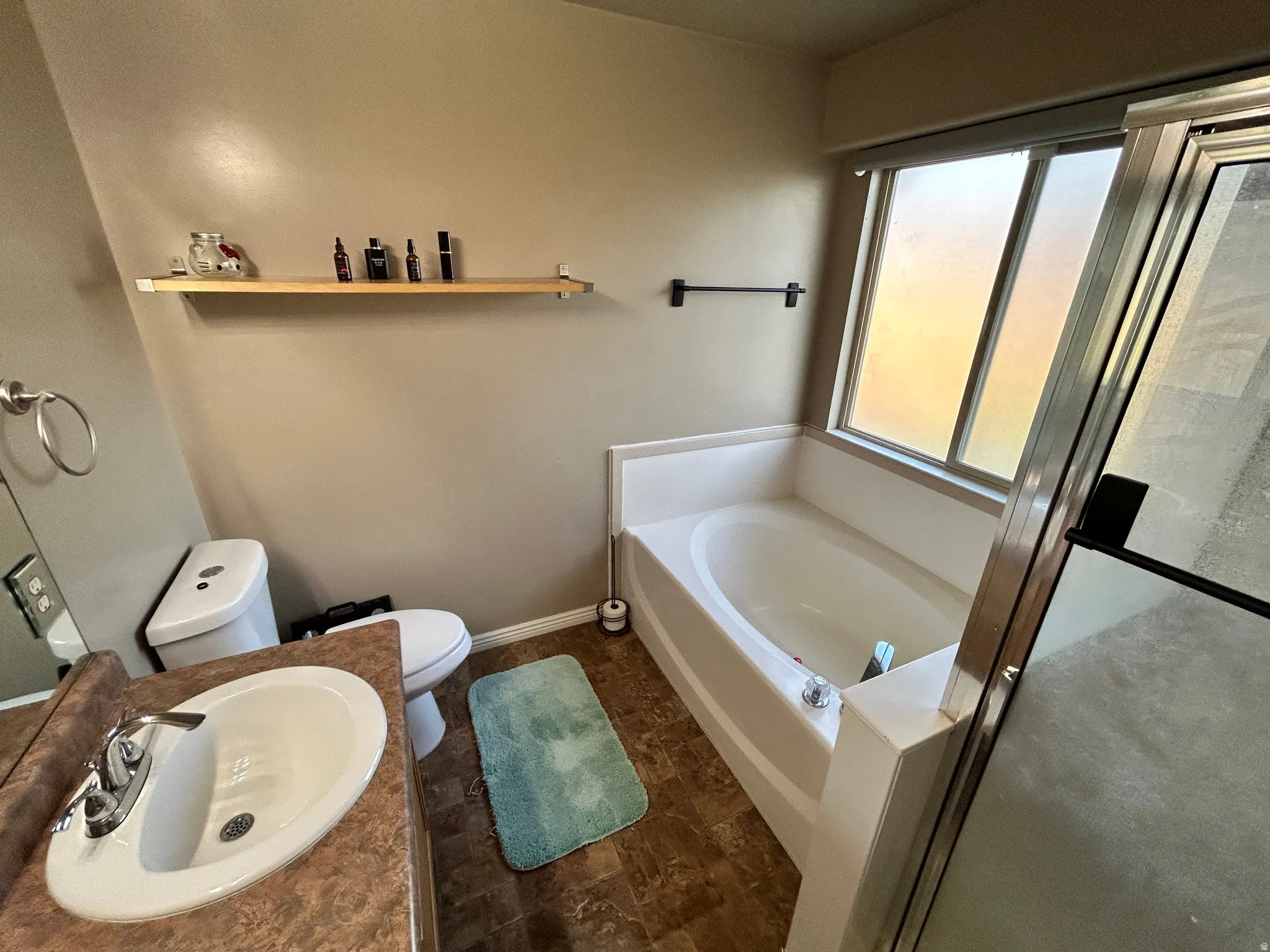 Built-in soaking tub, vanity with integrated sink, chrome faucet, window, and wood-finish flooring