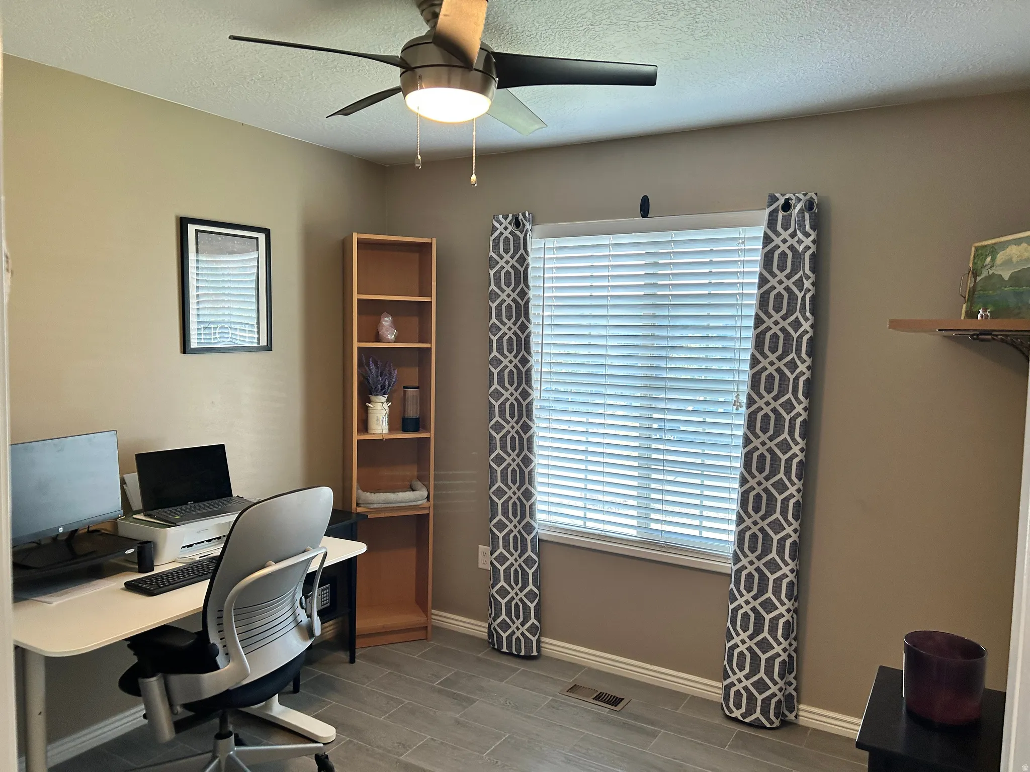 Home office featuring a wood-finish desk, ergonomic task chair, and dedicated work surface