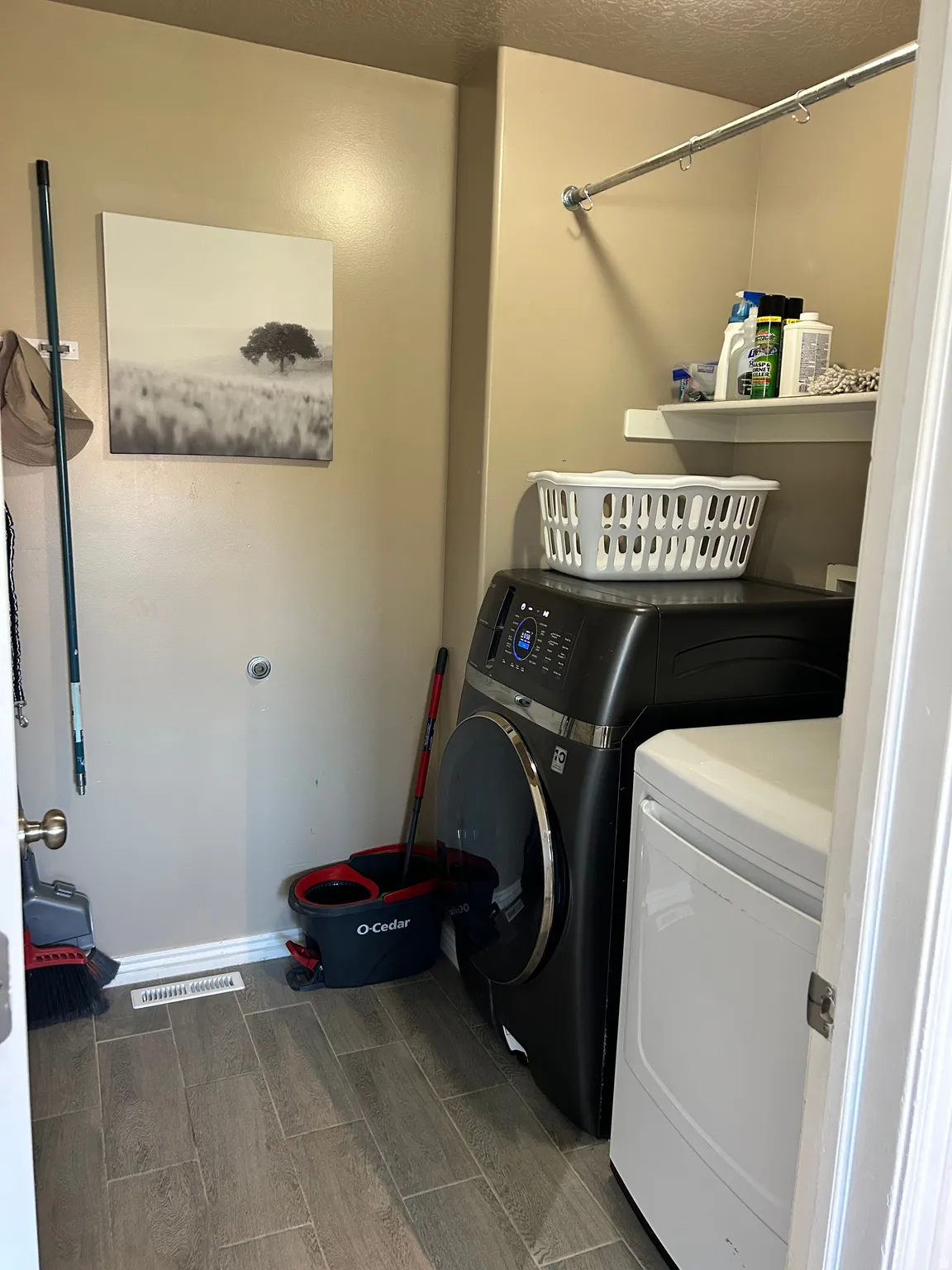 Wood-finish tile flooring, wall-mounted shelving, and a metal hanging rod