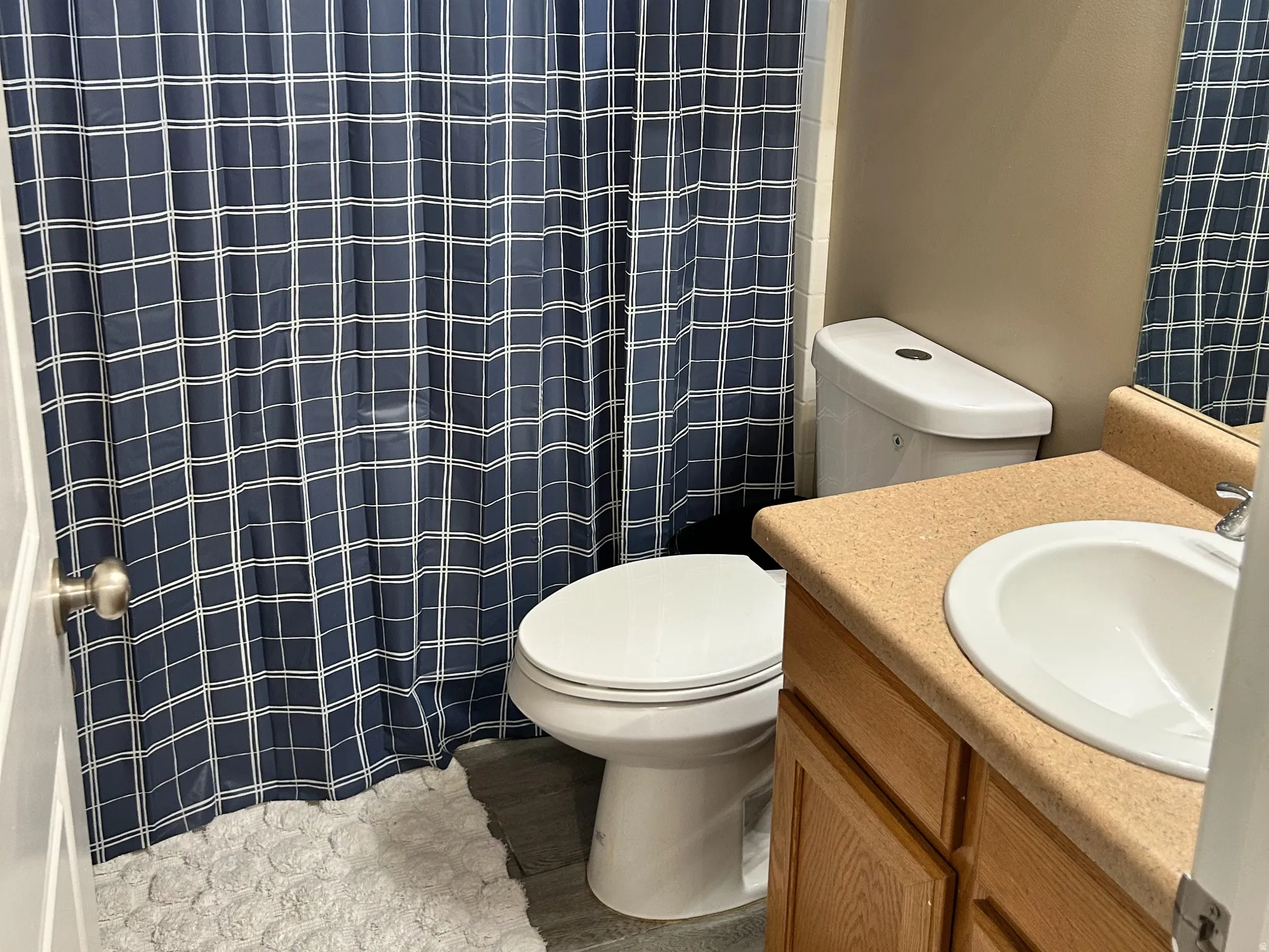 Full bathroom featuring a shower with a window, a single vanity with wood-finish cabinetry, and a white toilet